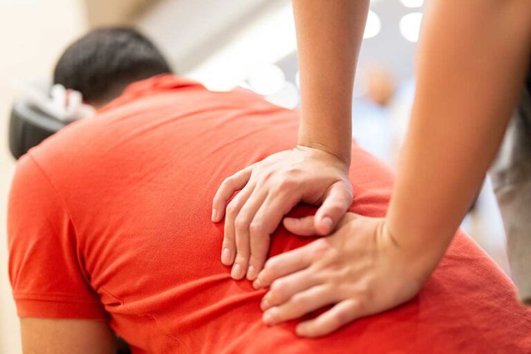 An athlete in athletic clothing receives a gentle spinal adjustment from a healthcare professional in a clinic setting.