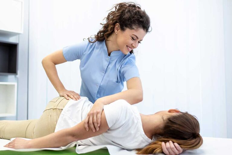 A child lying face down on a padded chiropractic table while a practitioner uses gentle hand pressure on their back.