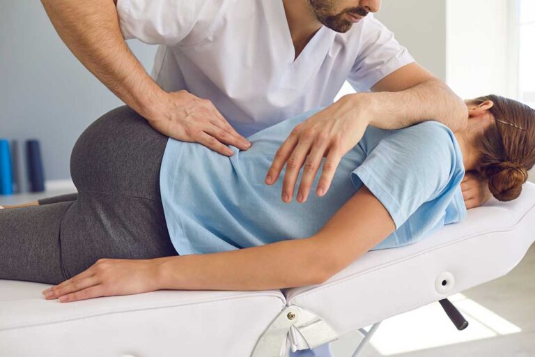 A chiropractor explains spine anatomy to a new patient seated in a consultation room.